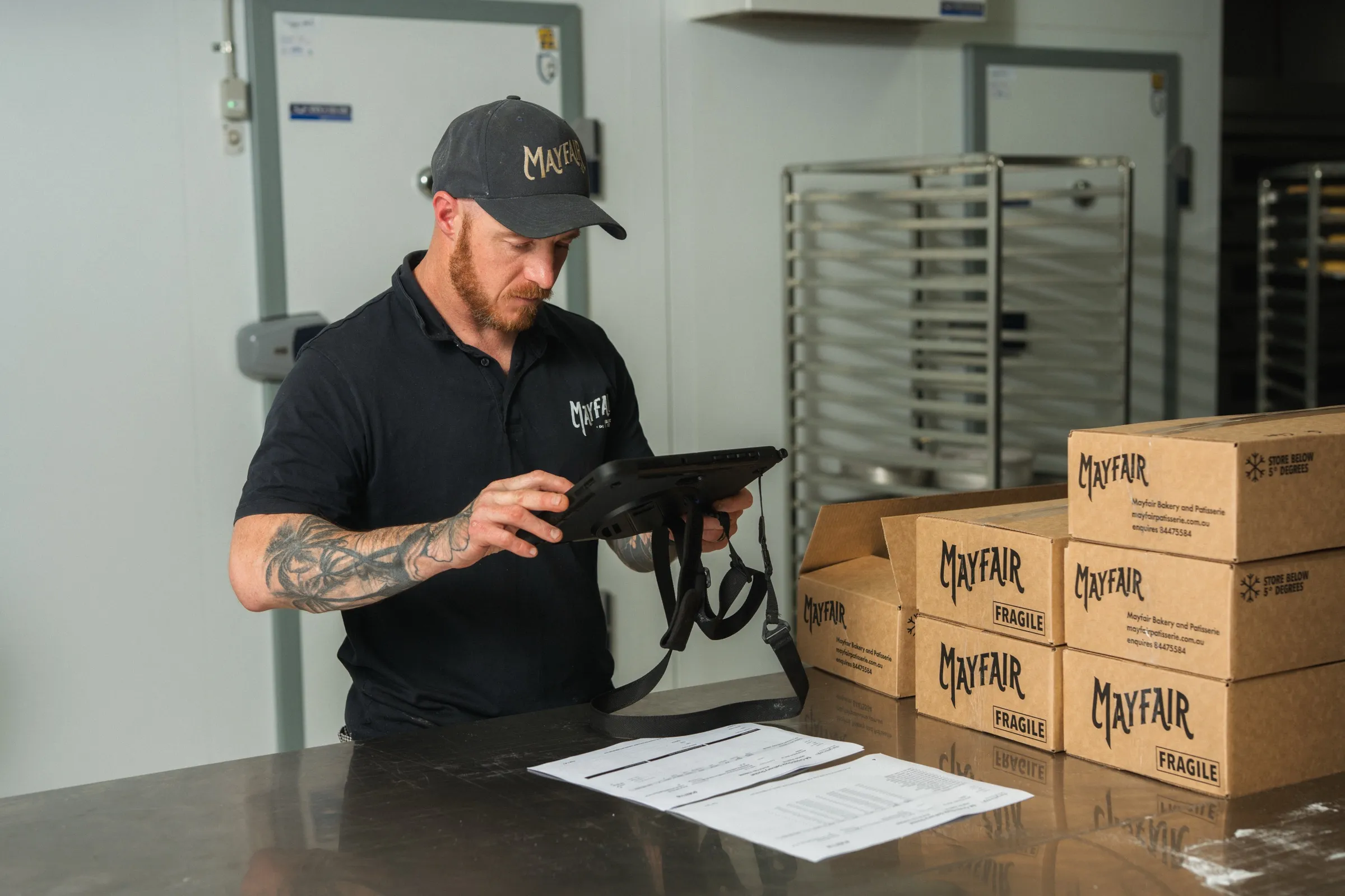 A Mayfair Bakery team member recording a dispatch on the Klara tablet beside packed boxes