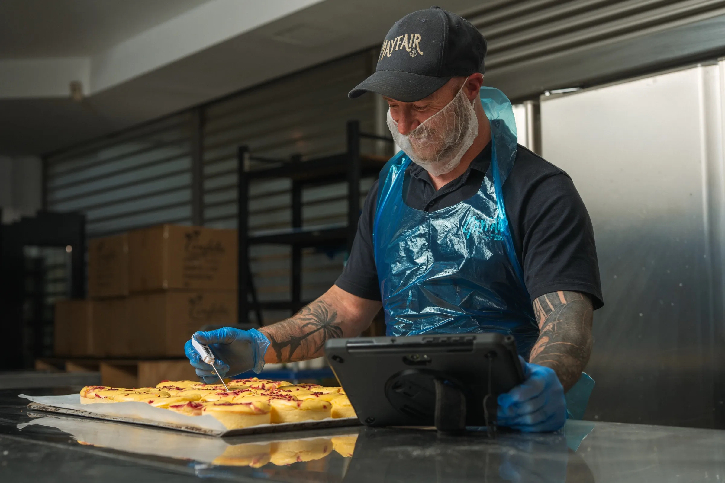 A Mayfair Bakery baker probing the temperature of cheesecakes, with the Klara tablet on the bench